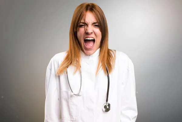 Νεαρός γιατρός γυναίκα φωνάζει σε γκρίζο φόντο — Φωτογραφία Αρχείου