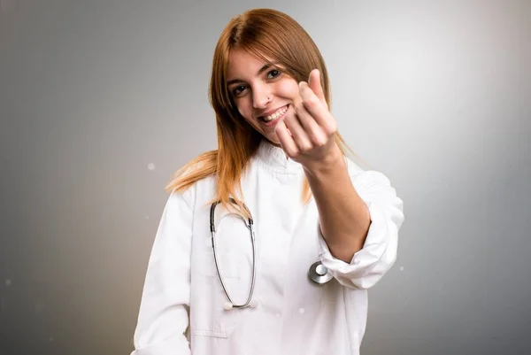 Молода лікарка заробляє жест на сірому фоні — стокове фото