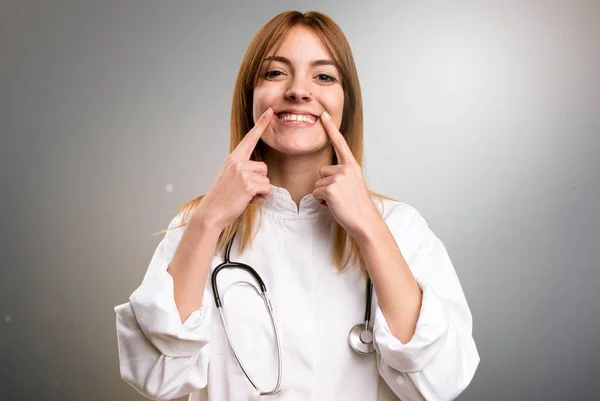 Gelukkig jonge dokter vrouw op grijze achtergrond — Stockfoto