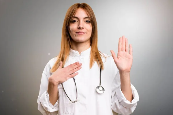 Jeune femme médecin faire un serment sur fond gris — Photo