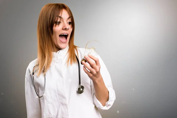 Jonge dokter vrouw met een lamp op grijze achtergrond — Stockfoto