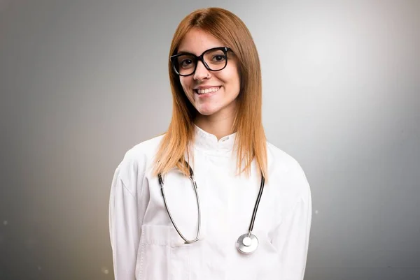 Молода лікарка в окулярах на сірому фоні — стокове фото