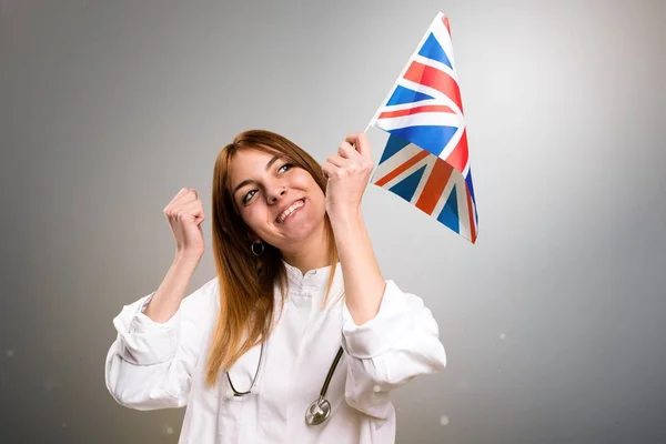 若い医者灰色の背景に英国のフラグを保持している女性 — ストック写真
