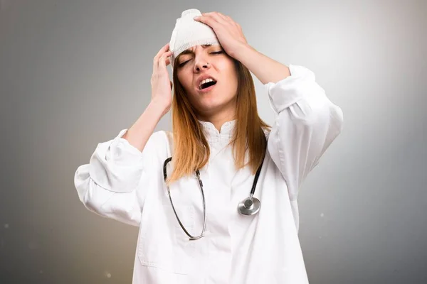 Jovem médica com dor de cabeça em fundo cinza — Fotografia de Stock