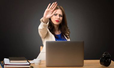 Onu laptop ile çalışma ve siyah arka plan üzerine dur işareti yapmak iş kadını