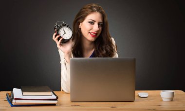 İş kadını ile çalışma saat onu laptop ve vintage tutarak siyah arka plan üzerine