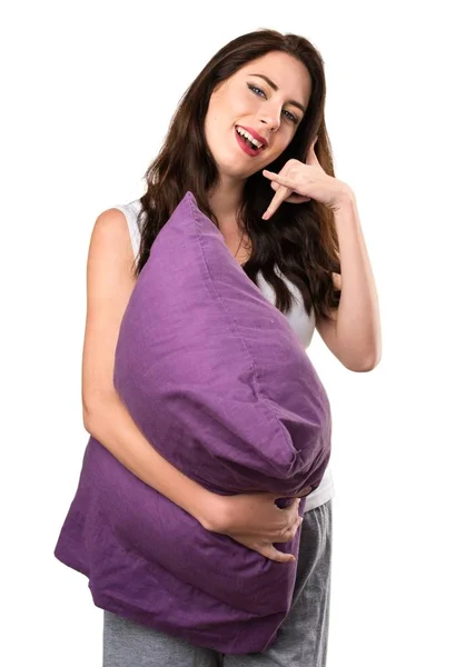 Beautiful young girl with a pillow making phone gesture — Stock Photo, Image