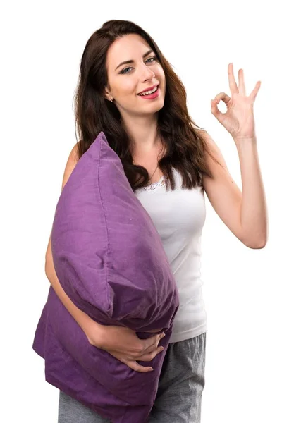Beautiful young girl with a pillow making OK sign — Stock Photo, Image