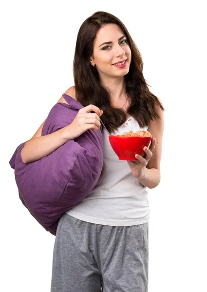 Menina bonita com um travesseiro segurando uma tigela de cereais — Fotografia de Stock