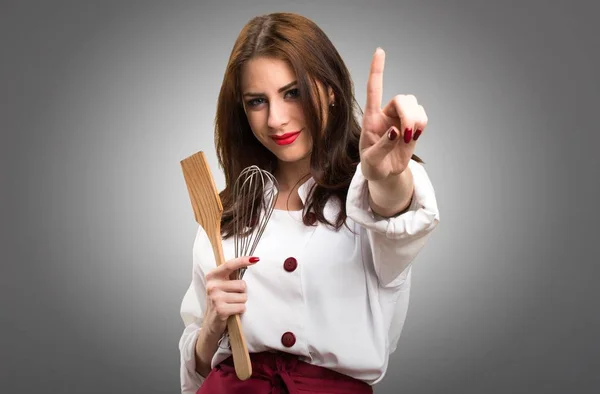 Hermosa mujer chef contando uno sobre fondo gris —  Fotos de Stock