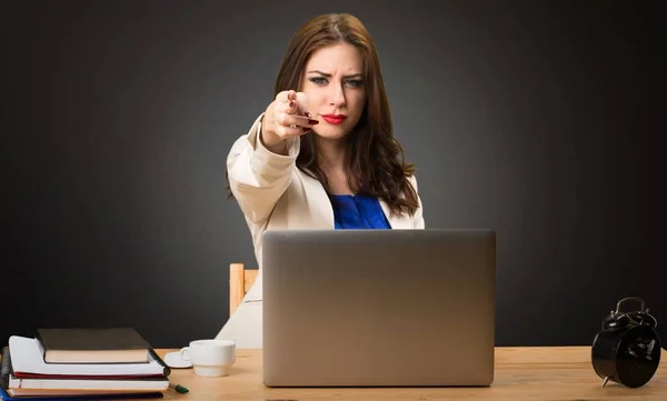 Business woman working with her laptop and making gun gesture on black background — Stock Photo, Image