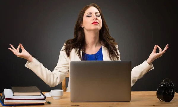 Obchodní žena pracující s její laptop a v pozici zen na černém pozadí — Stock fotografie