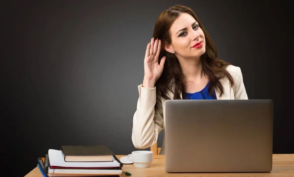 Zakenvrouw werken met haar laptop en luisteren iets op zwarte achtergrond — Stockfoto