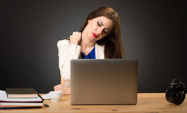 Бизнес-леди, работающая с ноутбуком и с болью в плече на черном фоне — стоковое фото