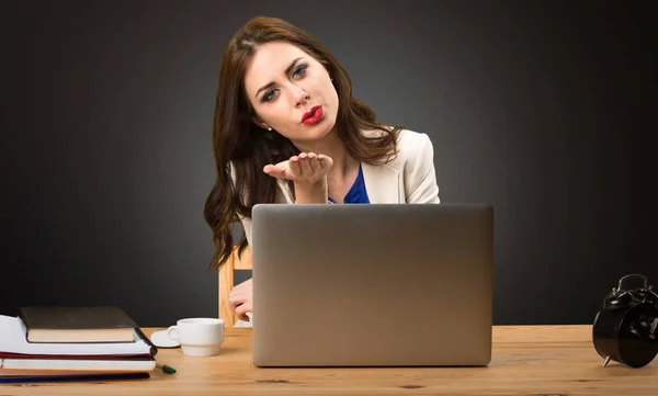 Zakenvrouw werken met haar laptop en een kus verzenden op zwarte achtergrond — Stockfoto