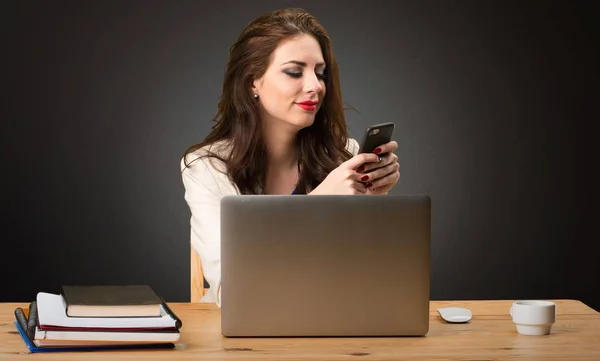 Femme d'affaires travaillant avec son ordinateur portable et avec son mobile sur fond noir — Photo