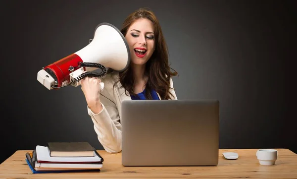 Obchodní žena pracující s laptopem a drží megafon na černém pozadí — Stock fotografie