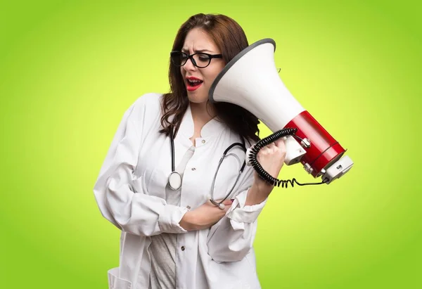 Dokter vrouw schreeuwen door megafoon op groene achtergrond — Stockfoto