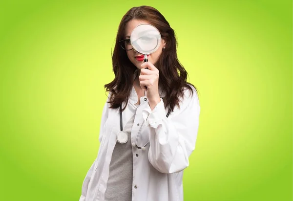 Доктор женщина с увеличительным стеклом на зеленом фоне — стоковое фото
