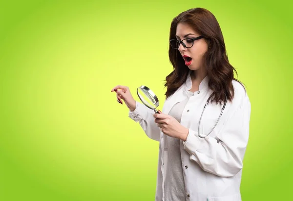 Läkare kvinna med förstoringsglas på grön bakgrund — Stockfoto