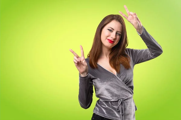 Hermosa chica joven haciendo gesto de victoria sobre fondo colorido — Foto de Stock