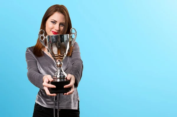 Beautiful young girl holding a trophy on colorful background — Stock Photo, Image