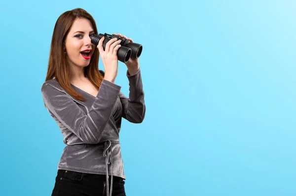 Hermosa joven con prismáticos sobre fondo colorido — Foto de Stock