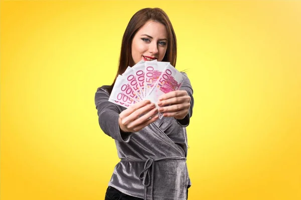 Hermosa chica joven tomando un montón de dinero en el fondo colorido — Foto de Stock