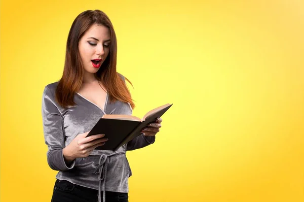 Beautiful young girl reading book on colorful background — Stock Photo, Image