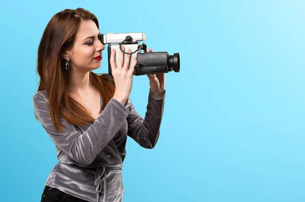 Beautiful young girl filming on colorful background — Stock Photo, Image