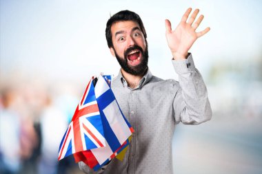 Birçok bayrak tutan ve selamlayan sakallı yakışıklı adam