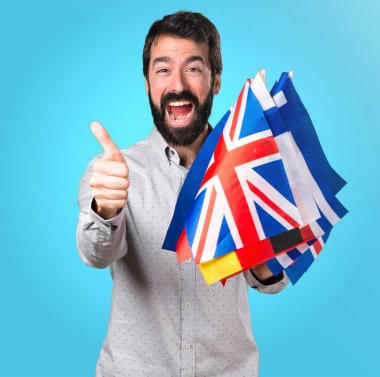 Birçok bayrak tutan sakallı ve başparmak ile yakışıklı adam