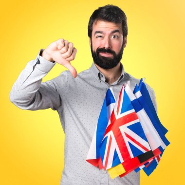 Birçok bayrak tutan ve kötü sinyal yapma sakallı yakışıklı adam