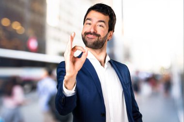 Yakışıklı adam Tamam odaklanmamış arka plan üzerinde kayıt yapma