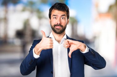 Yakışıklı adam iyi-kötü işaret odaklanmamış arka plan yapma