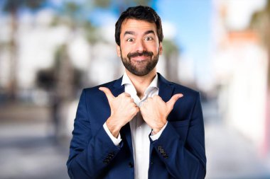 Yakışıklı adam odaklanmamış arka plan üzerinde başparmak ile