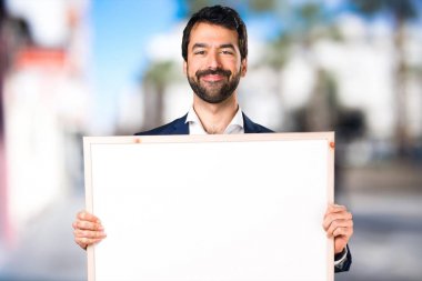 Yakışıklı adam boş bir afişini odaklanmamış arka planda tutan