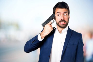 Yakışıklı adam odaklanmamış arka plan üzerinde bir tabanca tutan