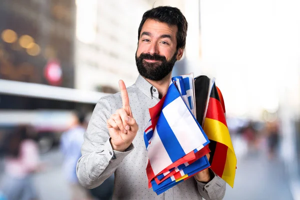 Homem bonito com barba segurando muitas bandeiras e contando uma — Fotografia de Stock