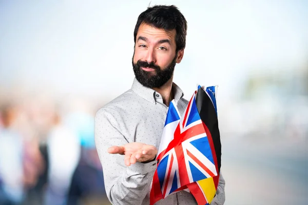 Stilig man med skägg håller många flaggor och hålla något — Stockfoto