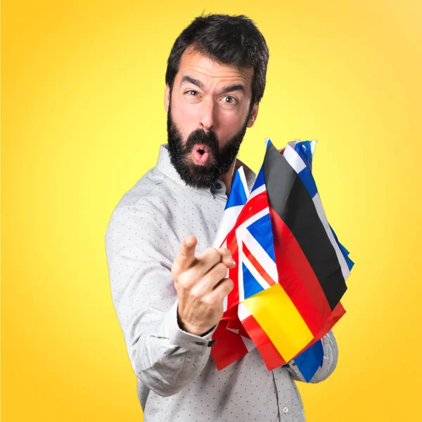 Bell'uomo con la barba che tiene molte bandiere e grida — Foto Stock