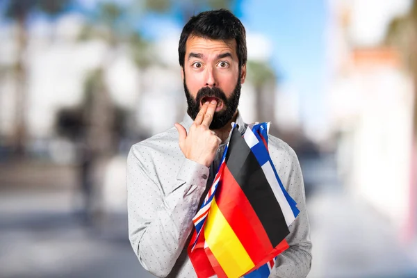 Bonito homem com barba segurando muitas bandeiras e fazendo vômitos g — Fotografia de Stock