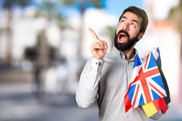 Stilig man med skägg håller många flaggor och tänkande — Stockfoto