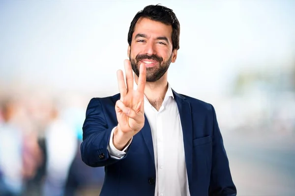 Bonito homem contando três com fundo desfocado — Fotografia de Stock