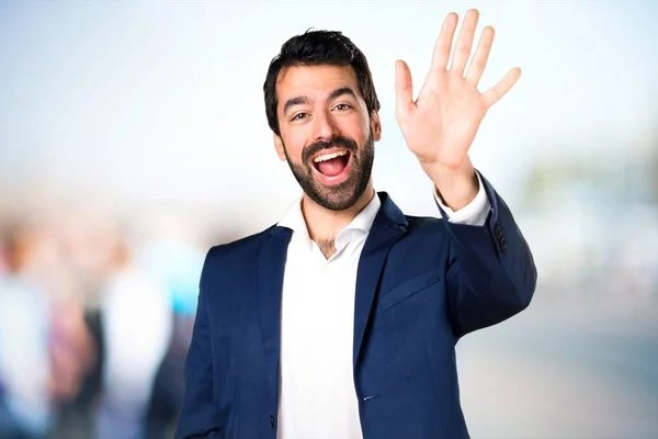 Schöner Mann salutiert auf unkonzentriertem Hintergrund — Stockfoto