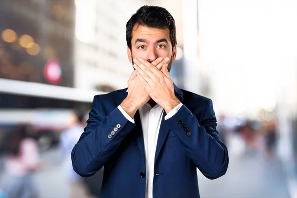 Hombre guapo cubriéndose la boca en un fondo desenfocado —  Fotos de Stock