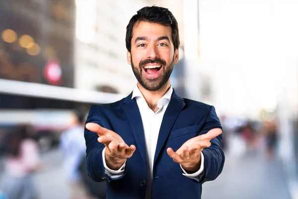 Hombre guapo presentando algo sobre fondo desenfocado — Foto de Stock