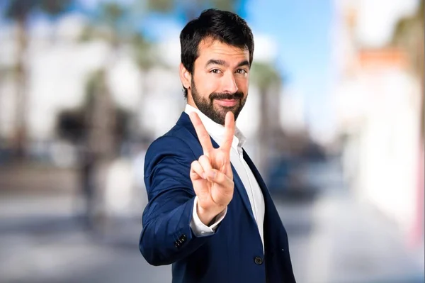 Pohledný muž dělat vítězství gesto na nezaostřený pozadí — Stock fotografie