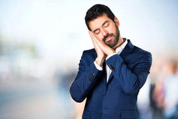 Handsome man making sleep gesture on unfocused background