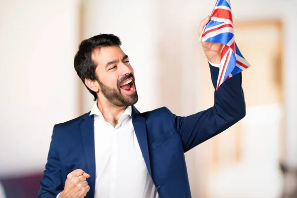 Bell'uomo che tiene una bandiera britannica su sfondo sfocato — Foto Stock
